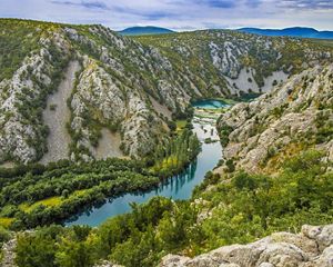 A canyon of the Krupa River that meanders through trees, plants and rocks.