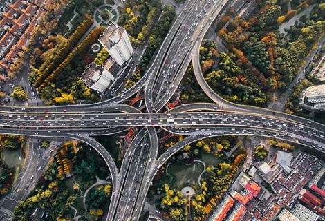 Aerial view looking down on a cloverleaf intersection of highways with many cars on the roads.
