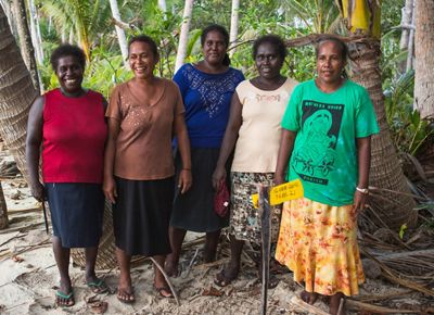 Five women pose for a group shot in a tropical forest.