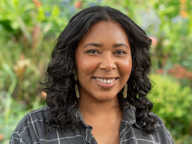 Headshot of a woman smiling in front of a green background.