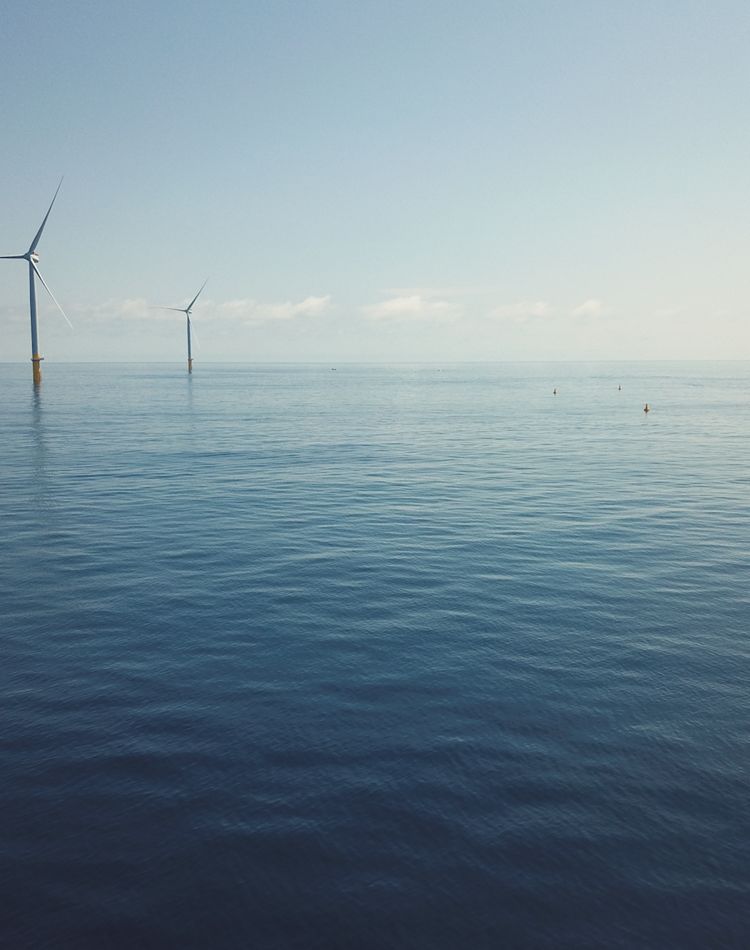 Two offshore wind turbines in the distance. 