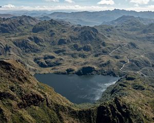 Aerial view looking down on a lake surrounded on all sides by tall mountains.